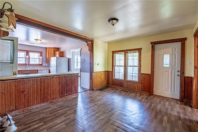 kitchen featuring dark wood finished floors, a wainscoted wall, white appliances, and a sink