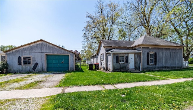 view of front facade featuring an outdoor structure, driveway, a front yard, and a detached garage