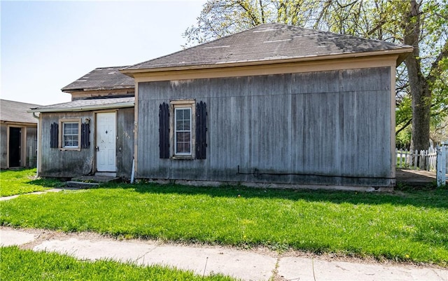 view of front of property featuring fence, a shingled roof, and a front lawn