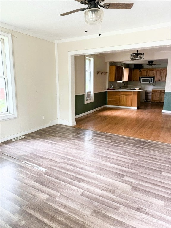 709 10th St, Charleston, IL 61920 - unfurnished living room with ceiling fan, light wood finished floors, crown molding, baseboards, and a sink