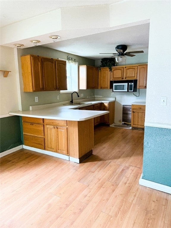 709 10th St, Charleston, IL 61920 - kitchen with stainless steel microwave, a sink, light wood-style floors, a peninsula, and light countertops