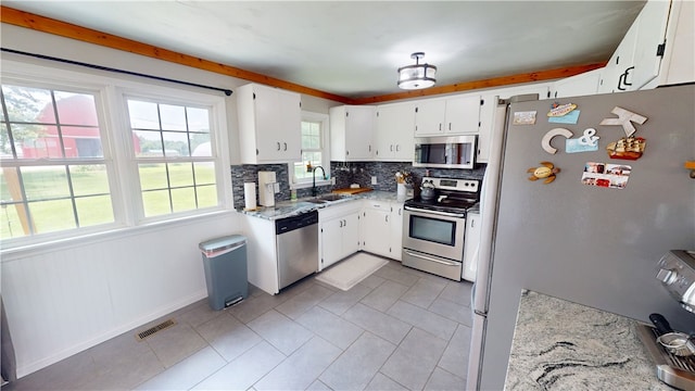 2251 W Stone Bluff Rd, Covington, IN 47932 - kitchen featuring stainless steel appliances, decorative backsplash, light stone counters, light tile patterned floors, and white cabinets