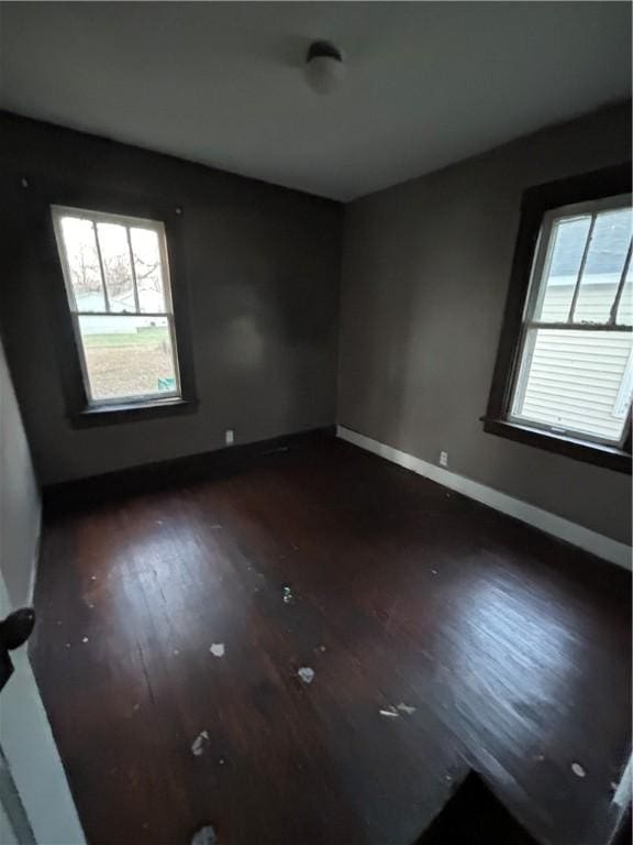 spare room with plenty of natural light and dark hardwood / wood-style flooring