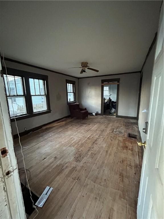 unfurnished living room featuring ceiling fan, wood-type flooring, and ornamental molding