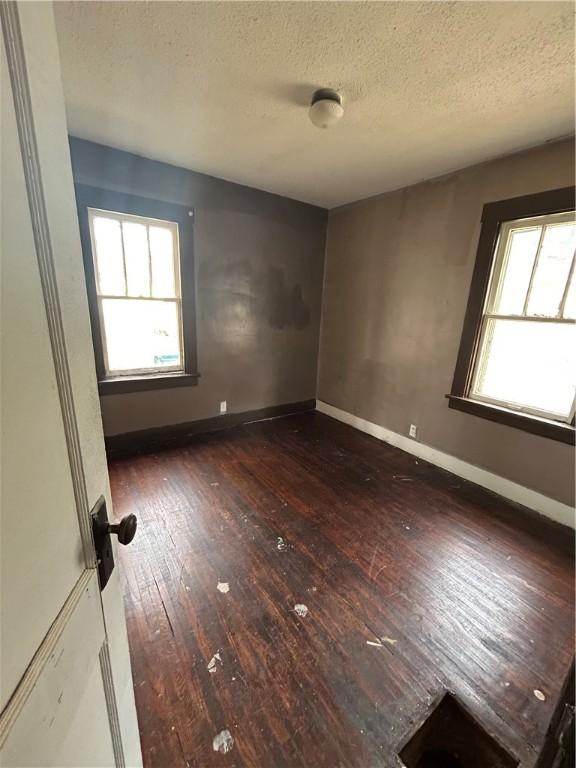 spare room featuring dark wood-type flooring and a textured ceiling