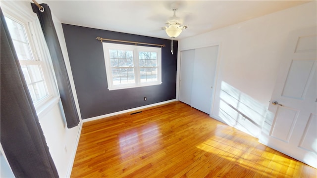 empty room with visible vents, ceiling fan, light wood-style flooring, and baseboards