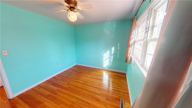 spare room featuring light wood-style floors, baseboards, visible vents, and a ceiling fan