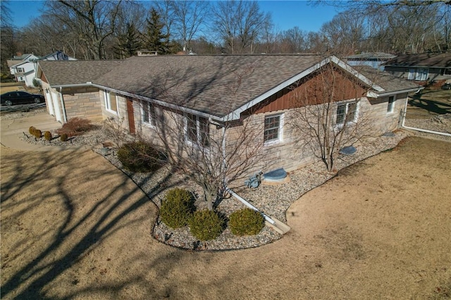 view of property exterior featuring stone siding and a shingled roof