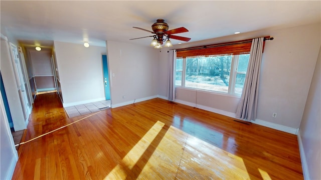 spare room featuring visible vents, ceiling fan, baseboards, and wood finished floors