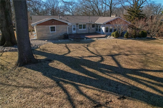 view of front of property featuring a patio, a shingled roof, central AC unit, a front yard, and stone siding