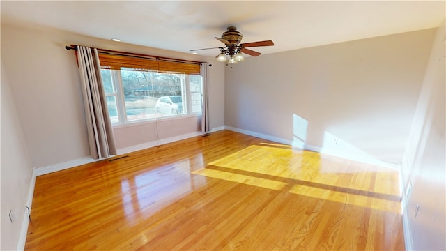 spare room featuring a ceiling fan, baseboards, and wood finished floors