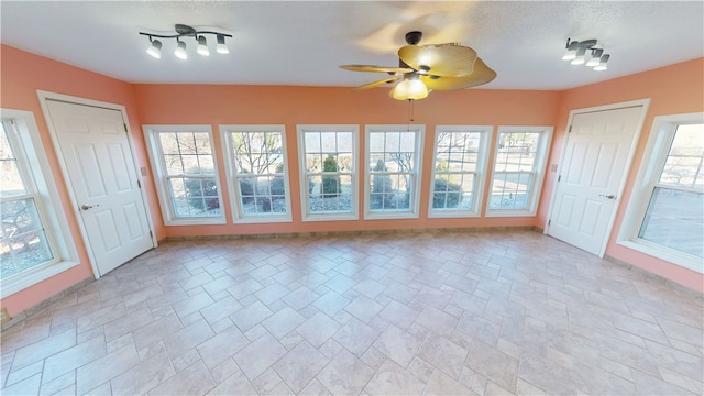 unfurnished sunroom featuring a ceiling fan