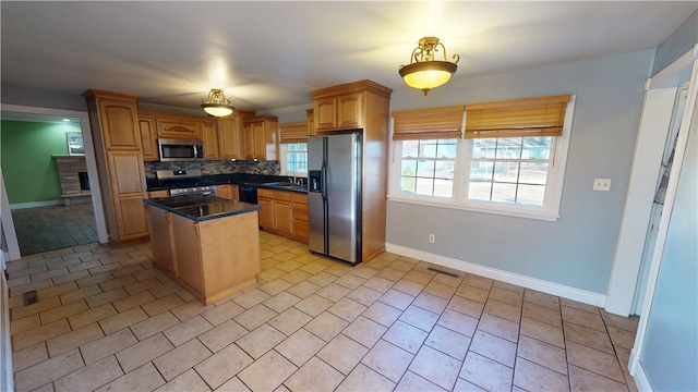 kitchen featuring visible vents, a center island, a sink, stainless steel appliances, and backsplash