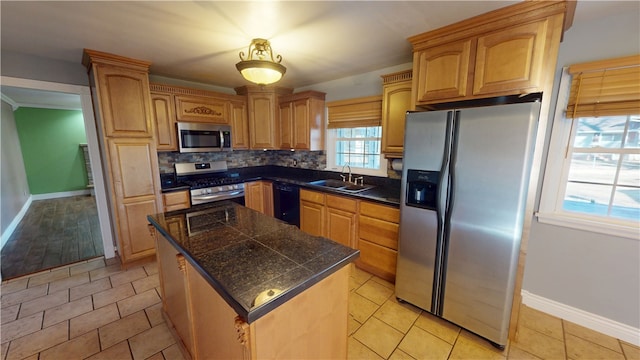 kitchen with a sink, a center island, appliances with stainless steel finishes, tile counters, and decorative backsplash