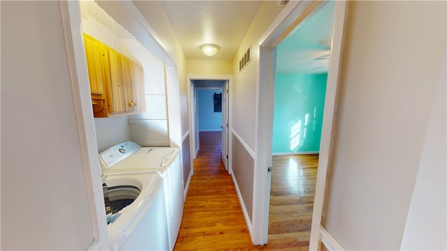 clothes washing area featuring visible vents, baseboards, light wood-style floors, independent washer and dryer, and cabinet space