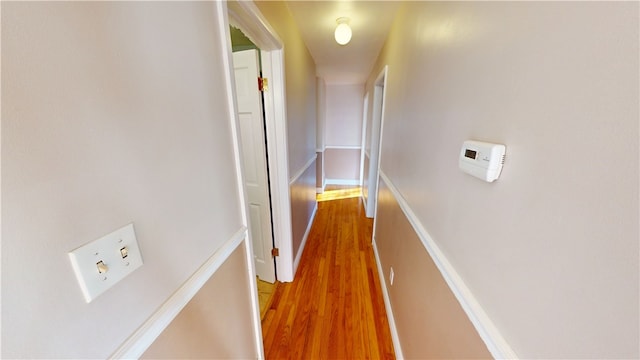 corridor with baseboards and wood finished floors