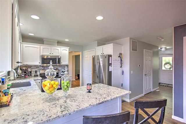 737 Phillip Cir, Forsyth, IL 62535 - kitchen with stainless steel appliances, a peninsula, white cabinetry, tasteful backsplash, and recessed lighting