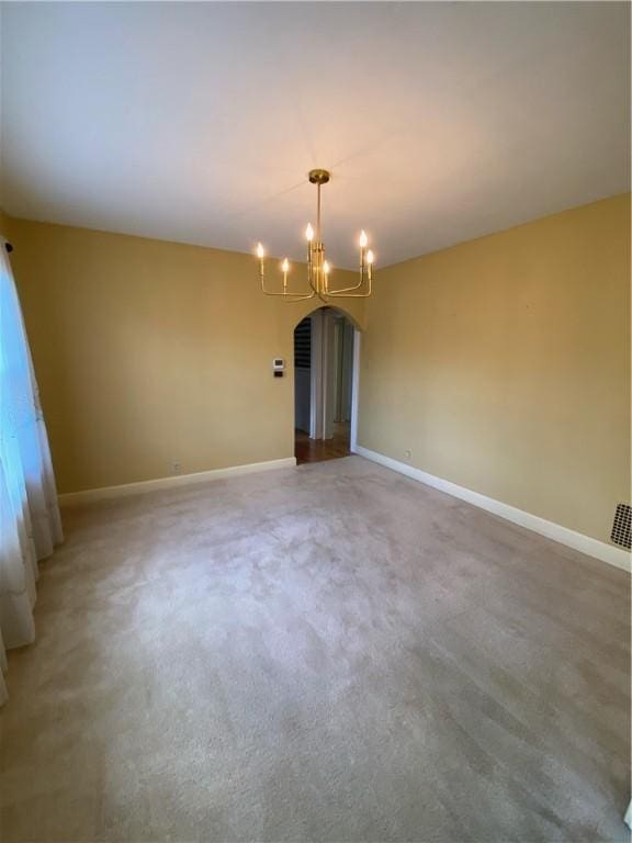 carpeted spare room with a notable chandelier