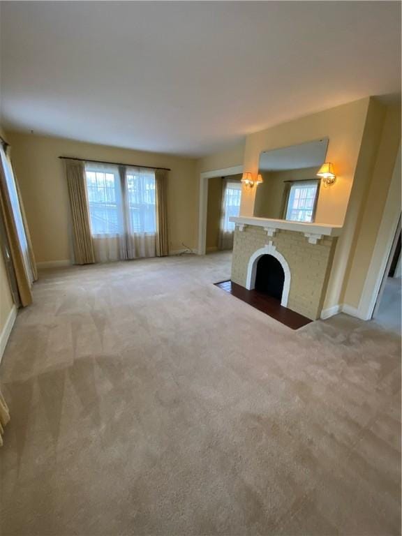 unfurnished living room featuring light colored carpet and a brick fireplace