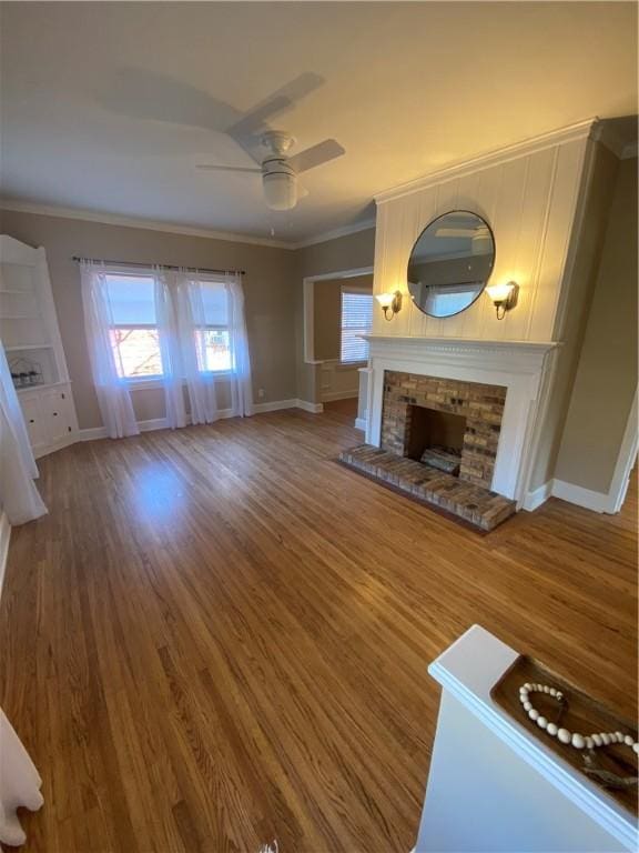 unfurnished living room featuring crown molding, a fireplace, ceiling fan, and hardwood / wood-style floors