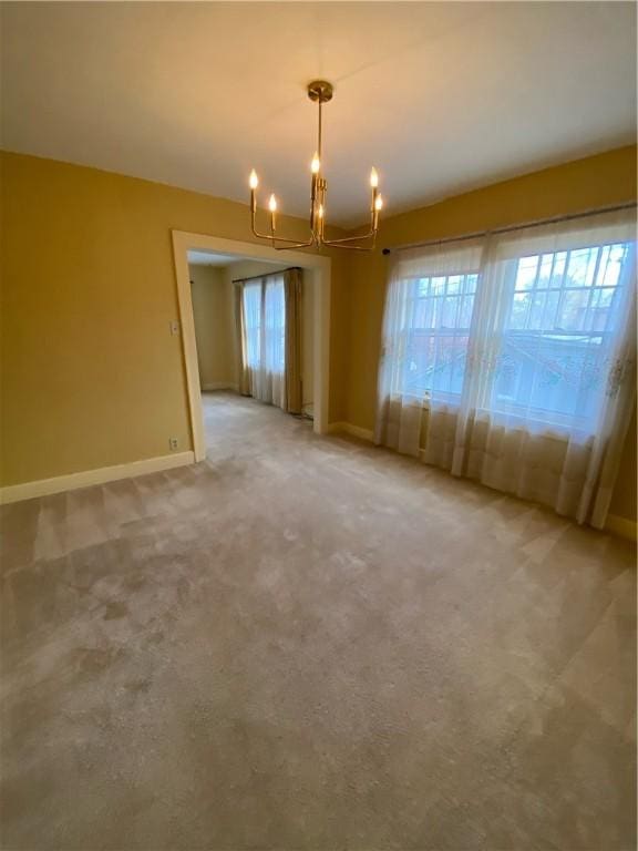 carpeted spare room with an inviting chandelier