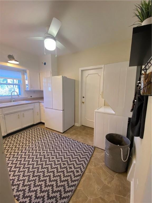 kitchen featuring white cabinets, ceiling fan, white refrigerator, and sink