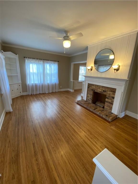 unfurnished living room with ceiling fan, wood-type flooring, and ornamental molding