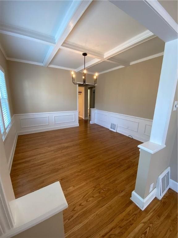 interior space with beam ceiling, coffered ceiling, an inviting chandelier, dark hardwood / wood-style floors, and crown molding