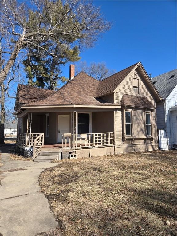 view of front of house with covered porch, roof with shingles, and a chimney