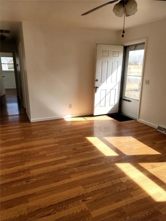 spare room with visible vents, ceiling fan, baseboards, and wood finished floors