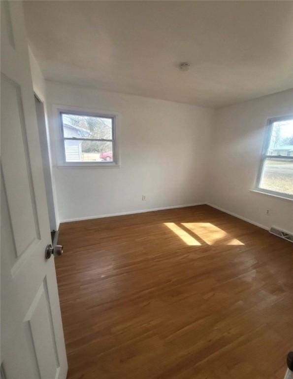 unfurnished room with visible vents, baseboards, and wood finished floors