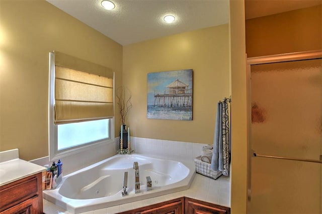 bathroom with vanity, shower with separate bathtub, and a textured ceiling