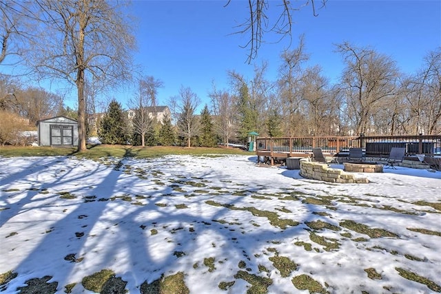 yard covered in snow with a wooden deck and a storage shed