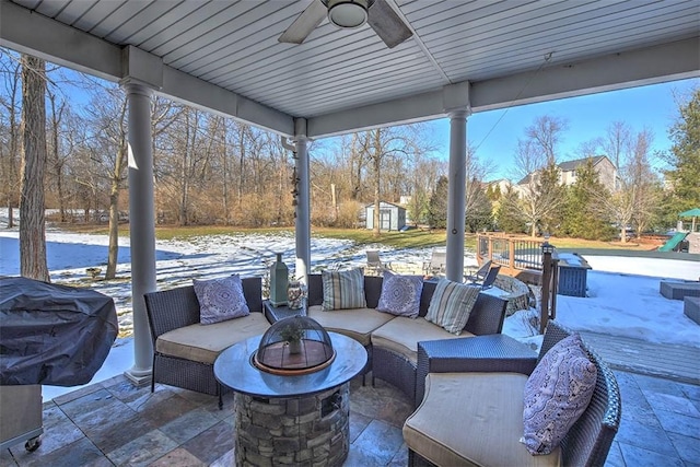 view of patio / terrace with grilling area, an outdoor living space with a fire pit, ceiling fan, and a storage unit