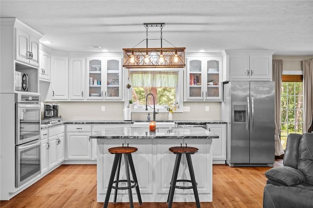 25760 E 1750th Rd, Marshall, IL 62441 - kitchen with appliances with stainless steel finishes, a kitchen breakfast bar, healthy amount of natural light, glass insert cabinets, and recessed lighting