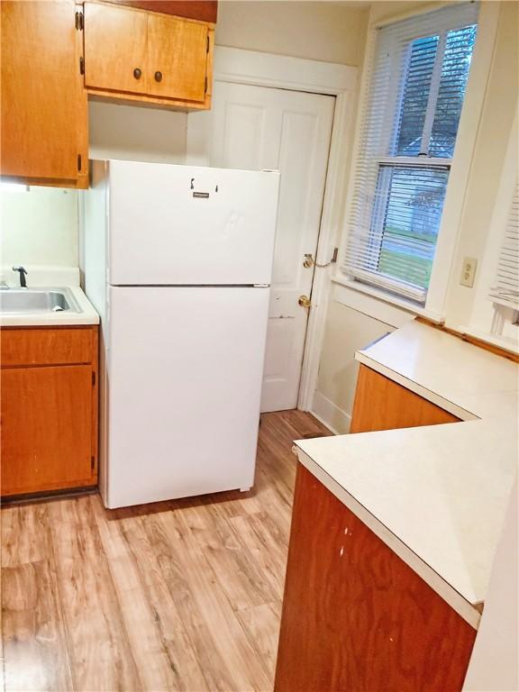 1009 S 14th St, Mattoon, IL 61938 - kitchen with freestanding refrigerator, a sink, light countertops, light wood-style flooring, and brown cabinetry