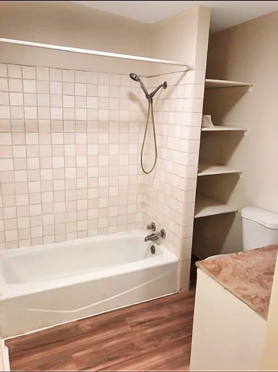 bathroom with toilet, tiled shower / bath combo, and hardwood / wood-style flooring