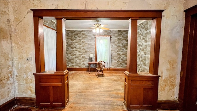 unfurnished room featuring hardwood / wood-style floors, ornate columns, ceiling fan, and crown molding