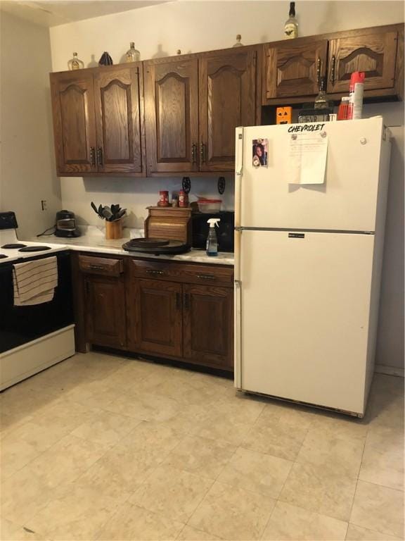 kitchen with dark brown cabinets, white refrigerator, and range