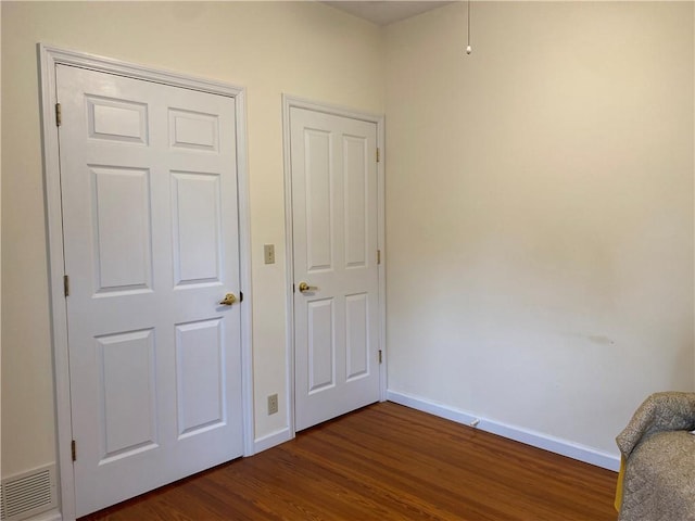 102 10th St, Charleston, IL 61920 - unfurnished bedroom with baseboards and dark wood-type flooring