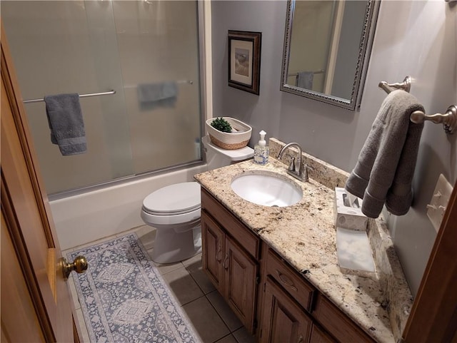 bathroom featuring tile patterned flooring, toilet, vanity, and enclosed tub / shower combo