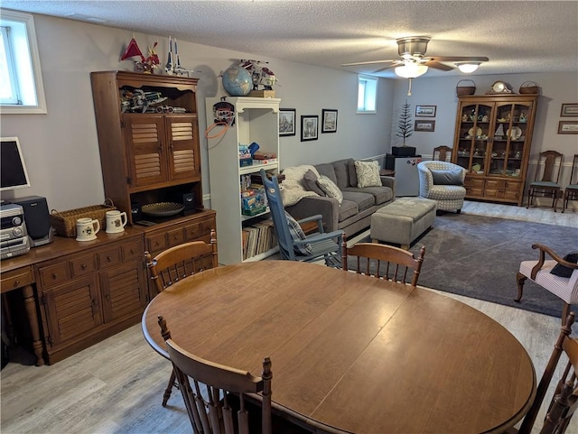 dining space featuring a ceiling fan, plenty of natural light, wood finished floors, and a textured ceiling