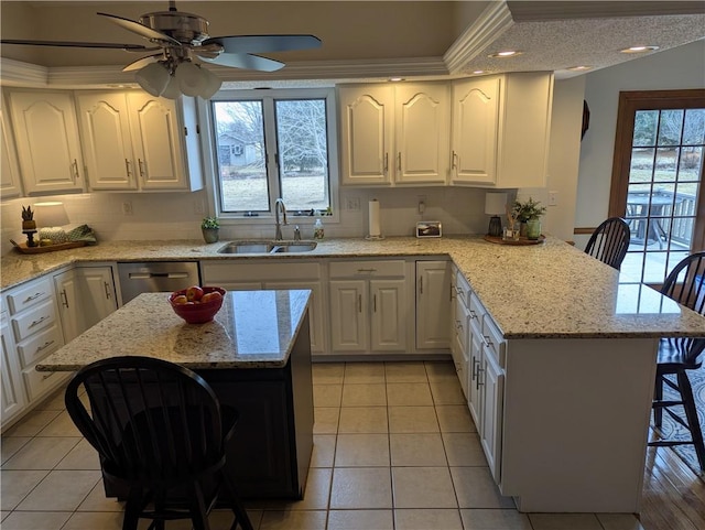 kitchen with a sink, dishwasher, a peninsula, and white cabinetry