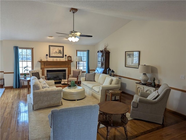 living room with lofted ceiling, a healthy amount of sunlight, wood finished floors, and a fireplace