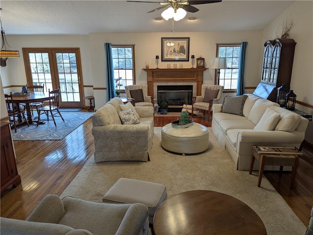 living room featuring a fireplace with flush hearth, wood finished floors, and ceiling fan