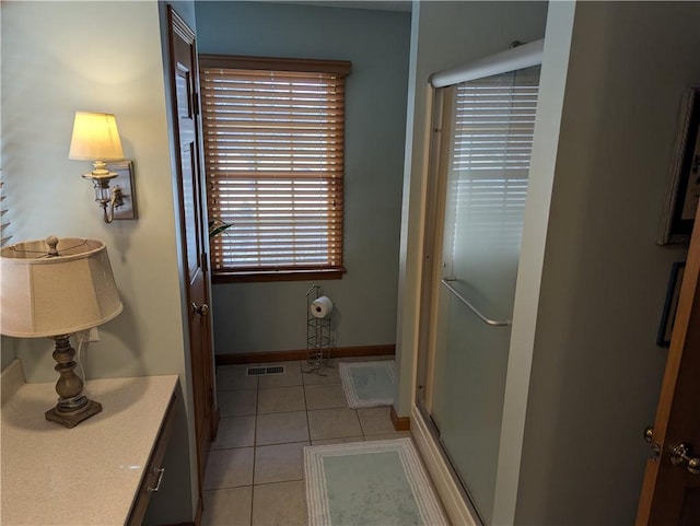 bathroom featuring tile patterned floors, visible vents, a shower with door, and baseboards