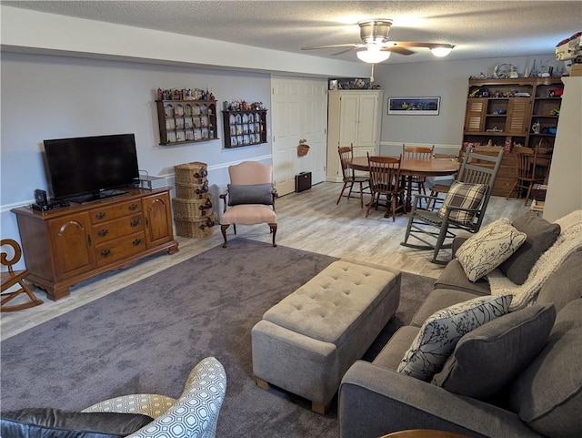 living area with a textured ceiling, ceiling fan, and wood finished floors