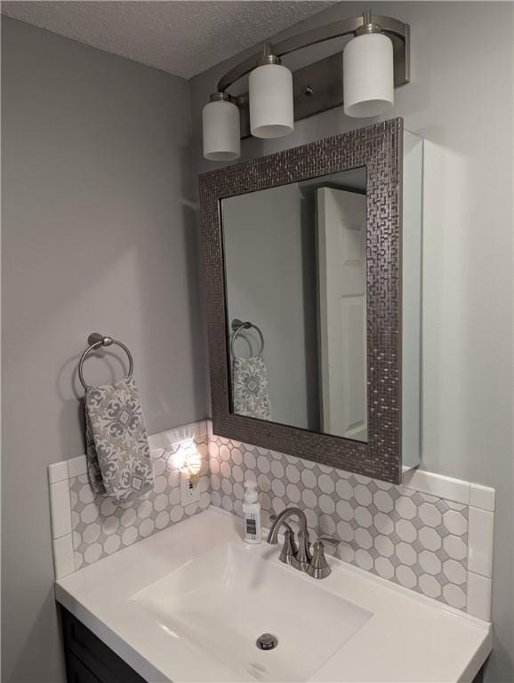 bathroom with decorative backsplash, a textured ceiling, and vanity