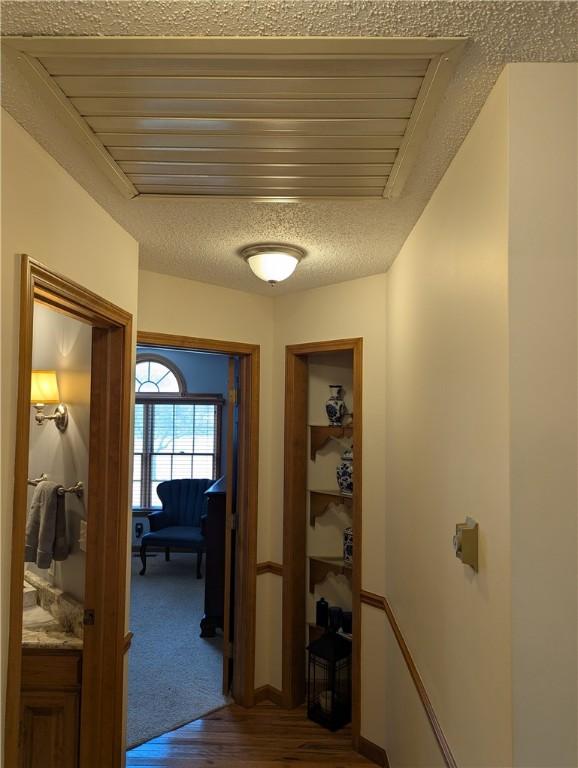 hall with dark wood-style floors, visible vents, and a textured ceiling