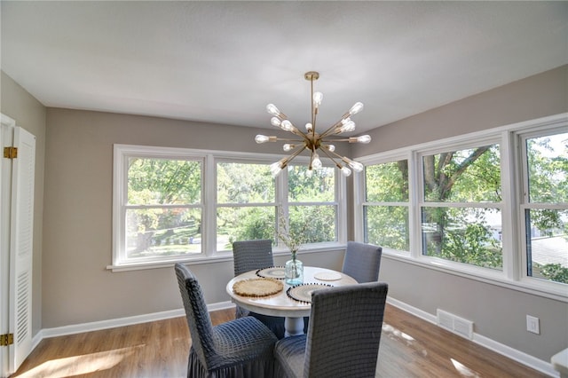 dining space with light hardwood / wood-style floors and a notable chandelier